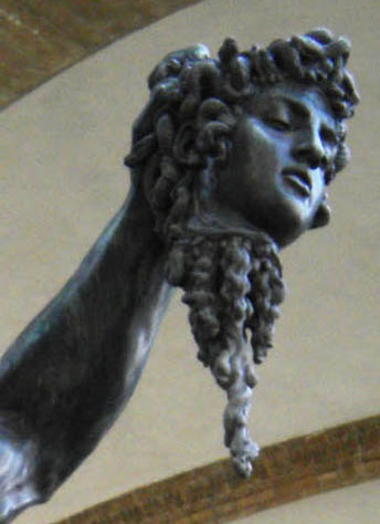 A zoomed-in shot of the severed head of Medusa. Her eyes are closed as if in sleep, and her face beautiful, her hair snakes curled up like the beautiful classical curls common on ancient statues. Bronze streams of gore come down from her neck as if she was just killed.