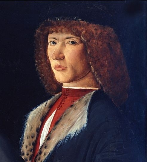 Portrait possibly of Galeazzo Sanseverino. A man with auburn shoulder-length curly hair stands looking at the viewer. He wears a black cap, a costly black velvet overgarment lined with leopard fur, a red doublet partly unbuttoned down the front, and gray gloves.