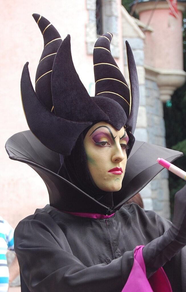 Cast member dressed as the Disney character Maleficent, wearing a horned headdress whose debt to the historical Hennin is more visible when it's rendered in real cloth.