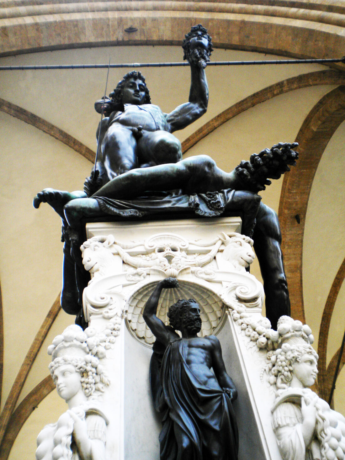 Another angle of the same statue from below shows the elaborate white base covered with decorations, and at the center a niche with a small statue of Jupiter, holding lightning aloft to threaten the viewer.