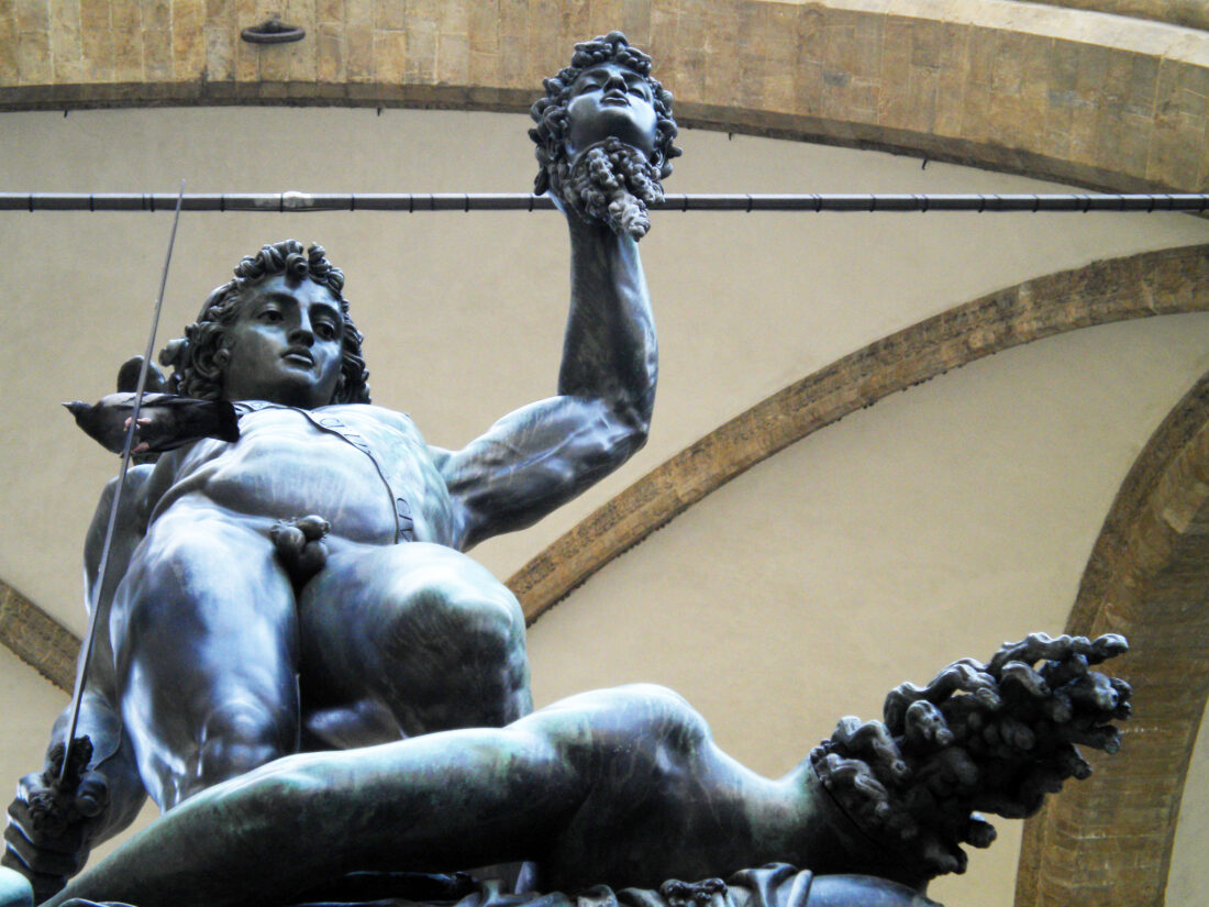 A photograph of the same statue angled from below shows how the sword, severed head, and the body's neck streaming gore all stick out forward from the body, so they can be in the rain while the body is under the roof above.