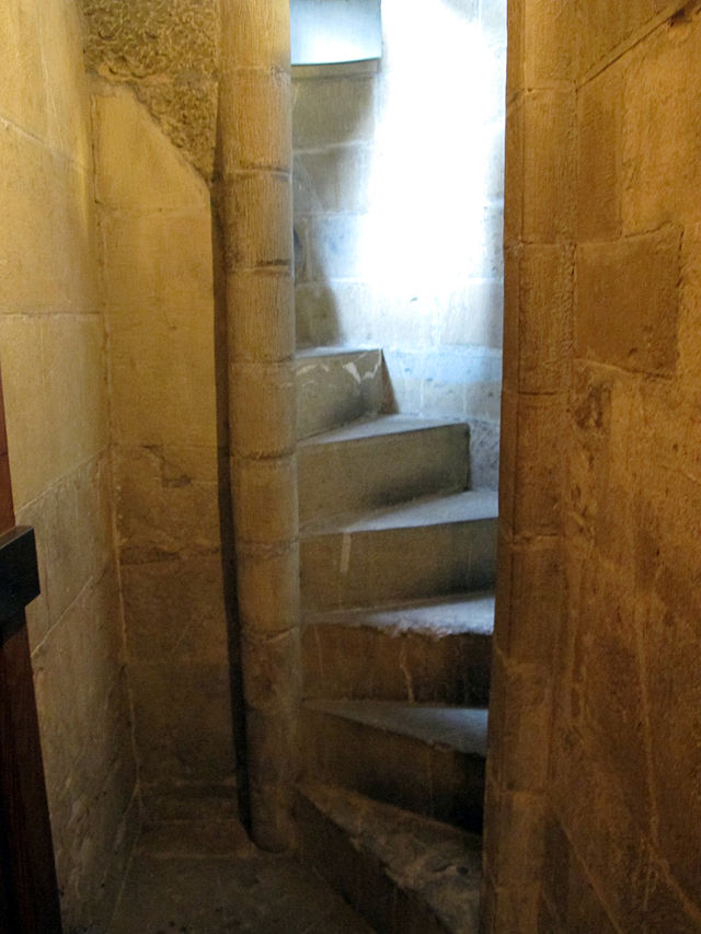 A narrow twisty stone staircase in a different part of the Palazzo Vecchio, cut of paler rougher stone and very steep, narrow, wedge-shaped, and twisting, with no banister to help!