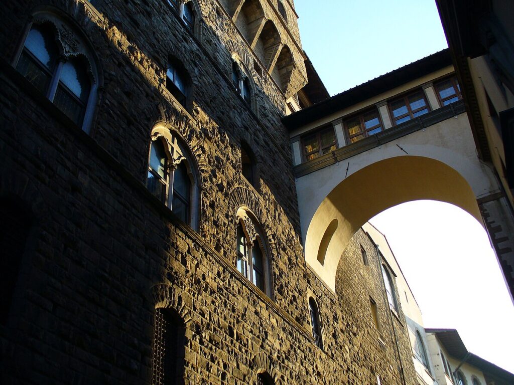 Outside of the Palazzo Vecchio, directly above those many flights of twisty stairs. An elevated walkway supported by an arch comes out of the wall and connects to the next building over, with a nice row of windows.