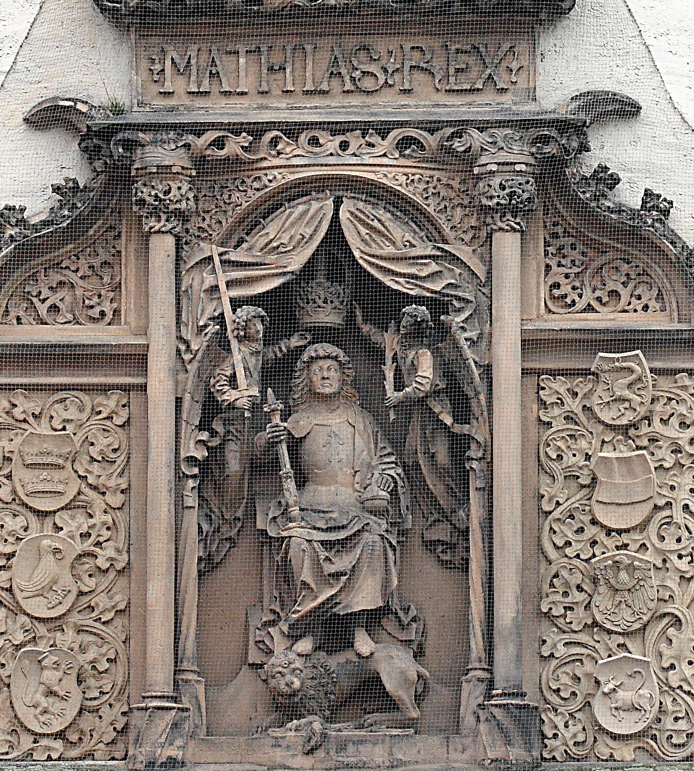 Impressive relief sculpture of Matthias Corvinus on a wall in Bautzen Ortenburg. The kin wears armor and has angels holding a crown above his head, one angel with a sword the other with an olive branch. The king holds a scepter and has his feet on a lion. Around him are carved ornate columns and vines, and above the inscription "MATHIAS REX"